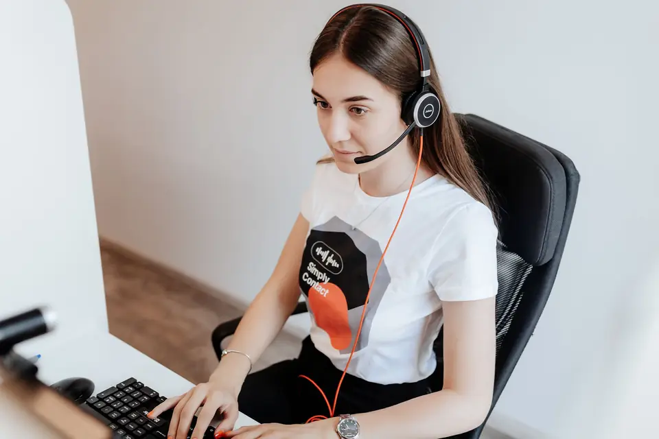 Agent Simply Contact cu căști, lucrând la calculator